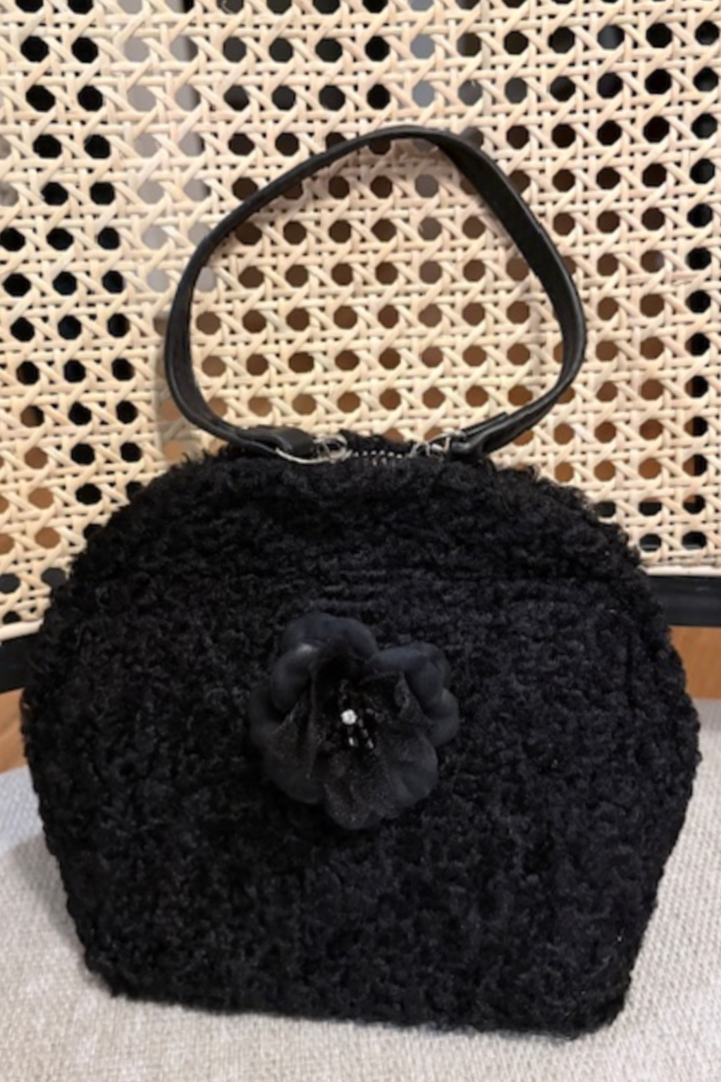 Black boucle top-handle bag with layered fabric flower front detail