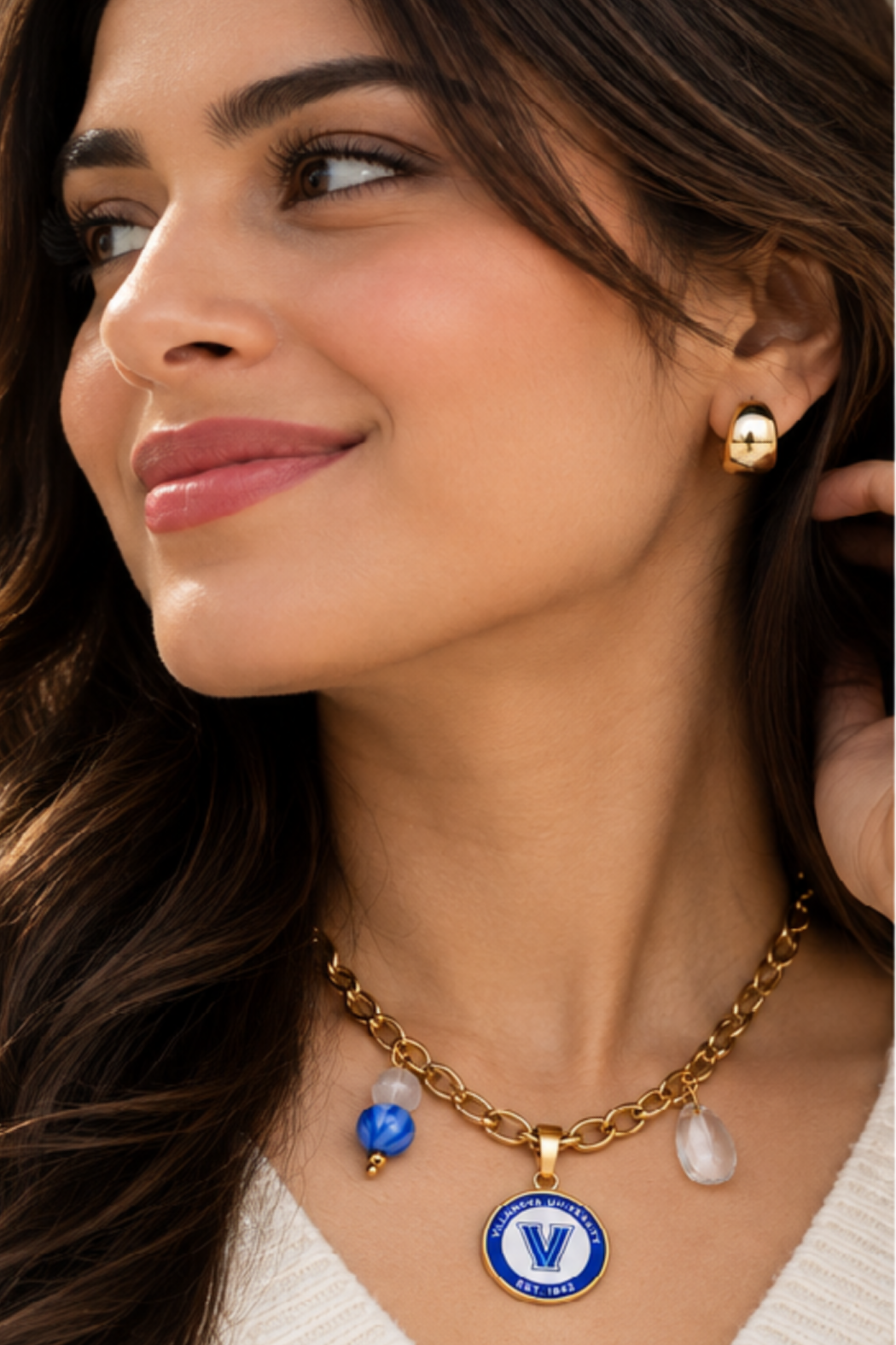 Villanova gold charm necklace with blue V medallion, blue bead, and teardrop charm
