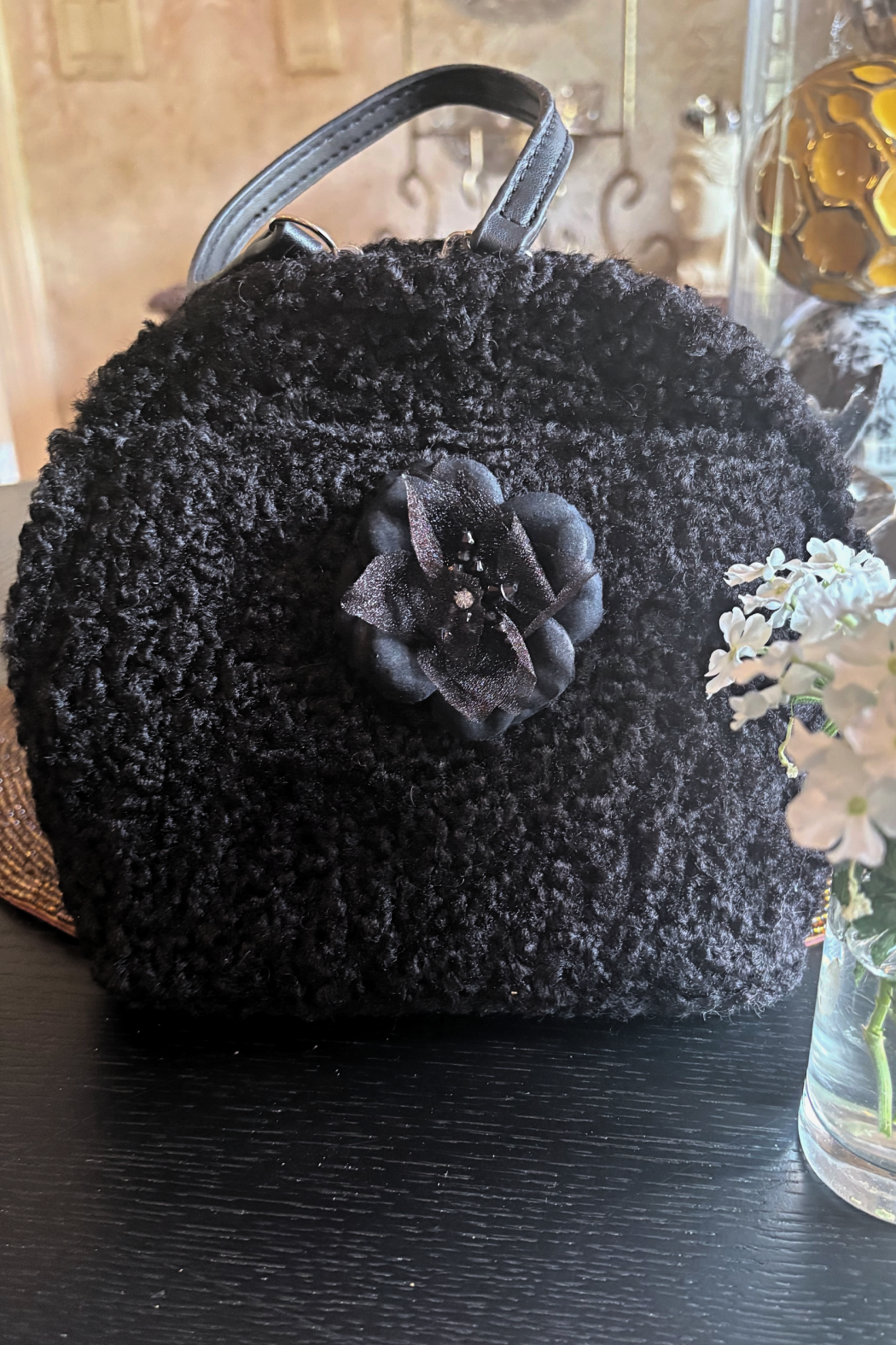 Black boucle handbag with curved handle and decorative flower front