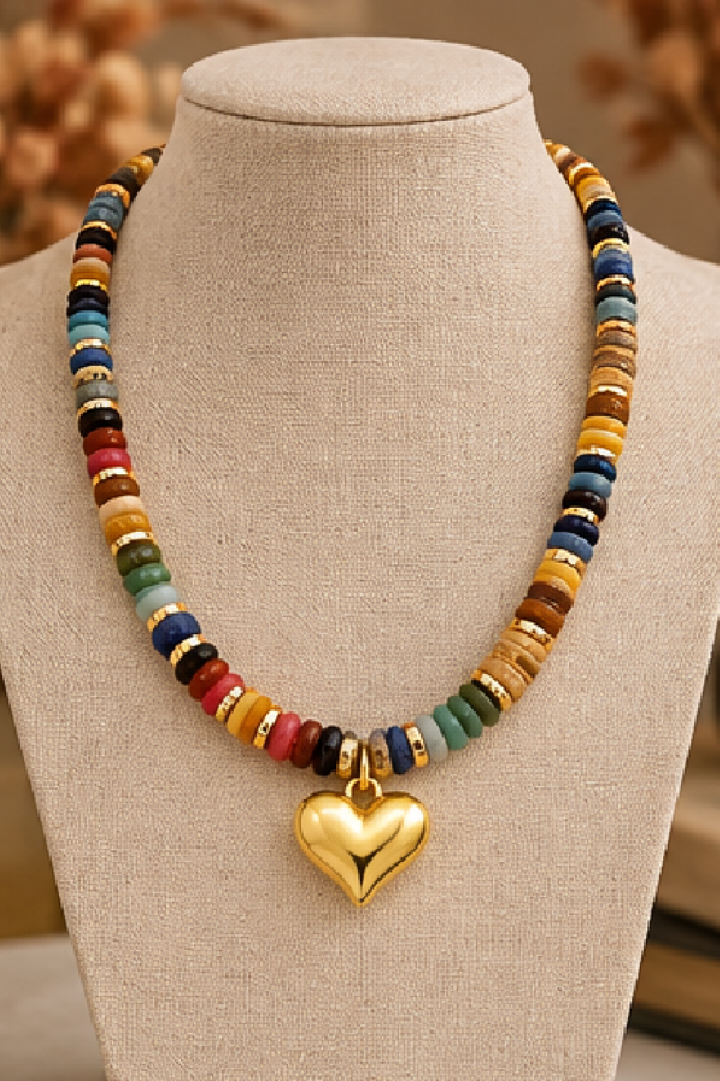 Multicolor beaded necklace with gold heart pendant on display stand