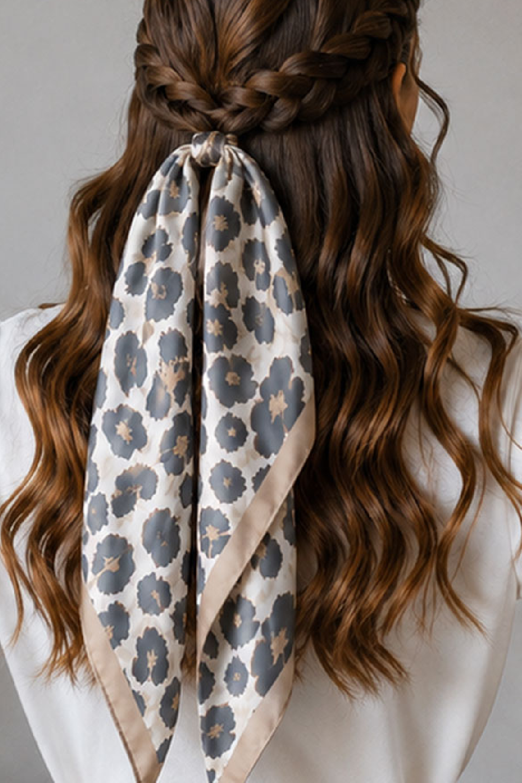 Leopard-print scarf with charcoal spots and taupe border, tied in braided hair