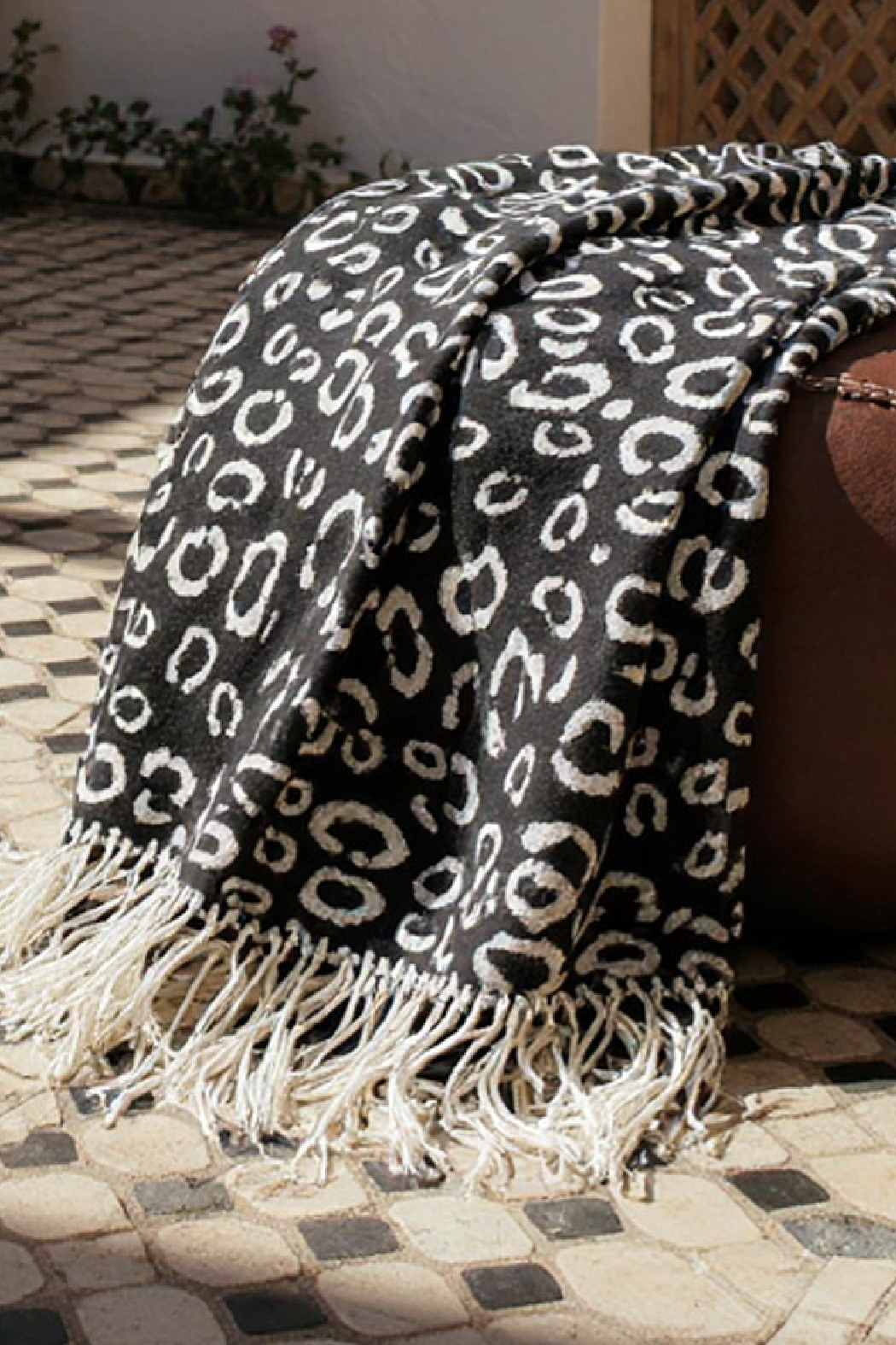 Black pashmina scarf with white leopard print and long fringe.